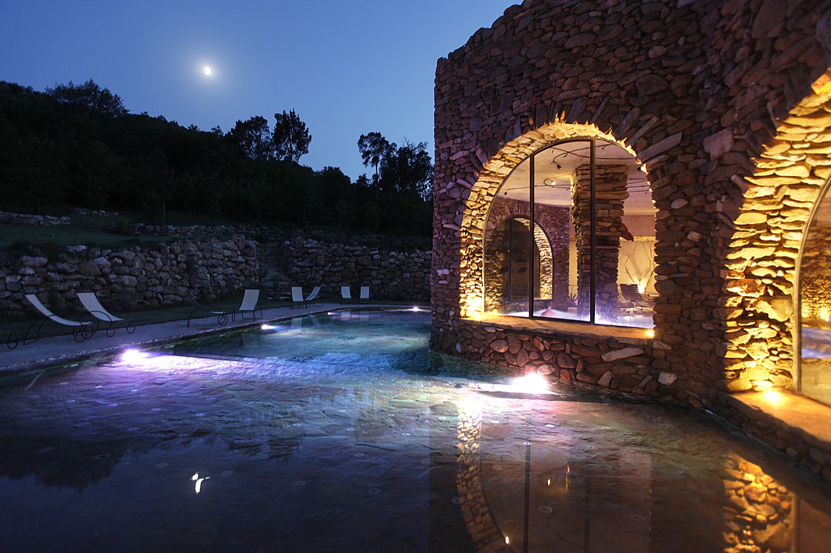 Terme di Sassetta al tramonto, luci nelle arcate e luna sul bosco